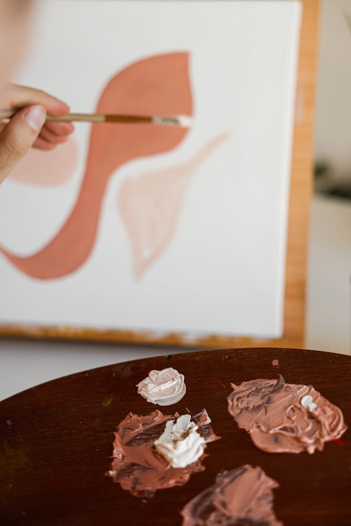 Close-up of an artist painting abstract shapes with a palette in view.